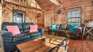 A cabin interior with two leather sofas, wooden flooring, a wooden ceiling, and a clock on the wall. - Cozy Cabin w/ 2 King Beds, Fireplace, Hot Tub, Foosball, Arcade and BBQ! (Sevierville)