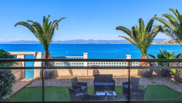 Une terrasse avec des sièges extérieurs, une vue sur la mer et un mur recouvert de carreaux formant un motif géométrique.