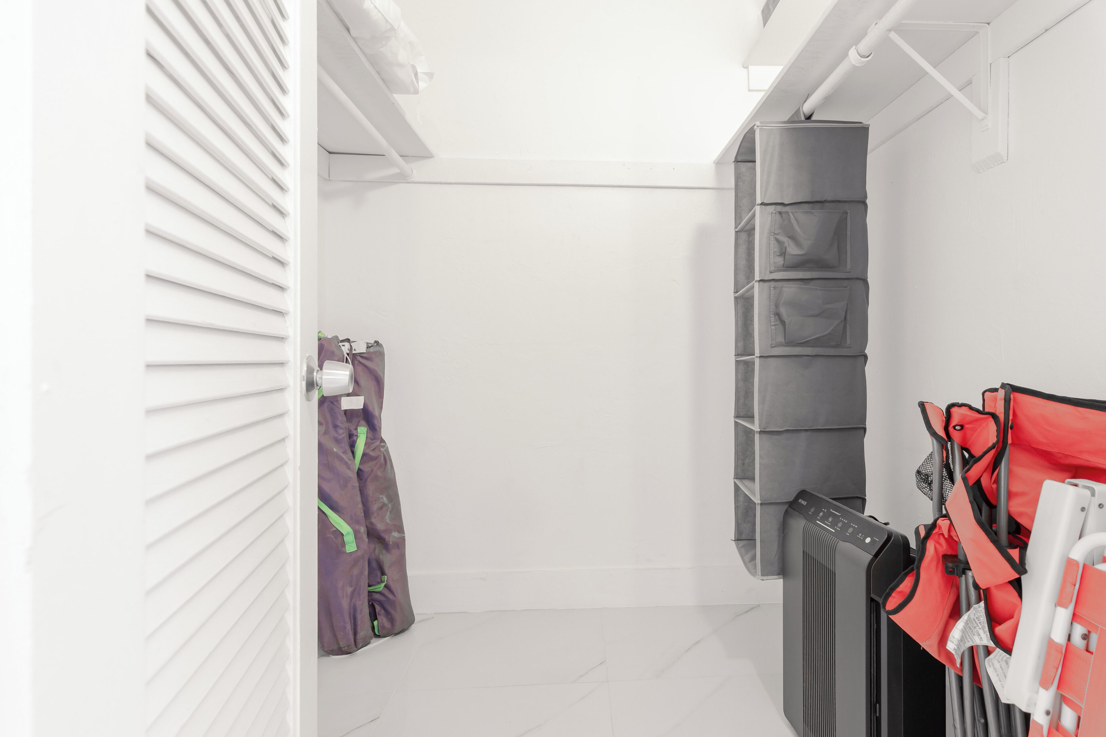 A narrow walk-through closet with storage shelves and a radiator.