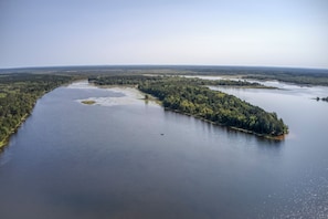 Luftaufnahme eines Flusses mit einer bewaldeten Insel und blauem Himmel.