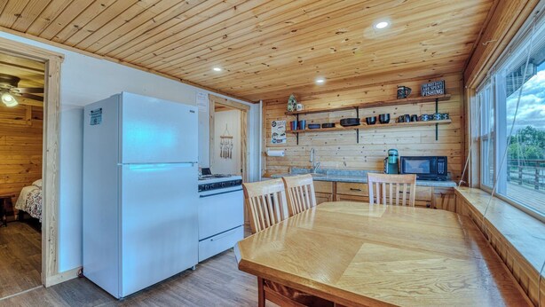 L’intérieur d’un chalet en bois comprend une cuisine, un coin repas et une grande fenêtre.