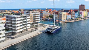 En lysthavn med farverige bygninger, en moderne lejlighedsbygning og en sejlbåd ved kaj.