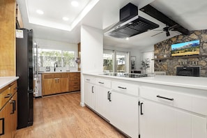 A modern kitchen with white cabinets, a black refrigerator, and a stone accent wall.