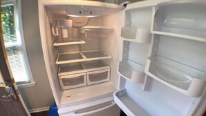 A white refrigerator with multiple shelves and compartments, a blue cleaning tool, and a window with blinds. - Spacious 1BR - Great Location @ Grandview & OSU! (Columbus)
