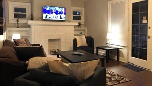 A living room with a fireplace, a television, and seating. - Spacious 1BR - Great Location @ Grandview & OSU! (Columbus)