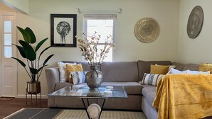 A living room with a sofa, a coffee table, a vase with flowers, and a large window. - Westerville Comfort & Convenience (Westerville)