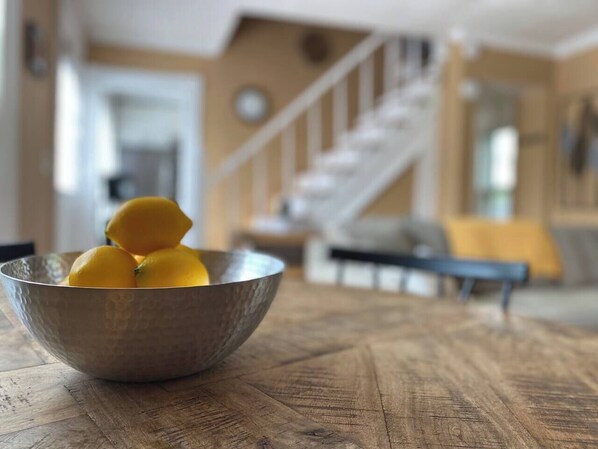 Una mesa de madera con un tazón de metal lleno de limones.