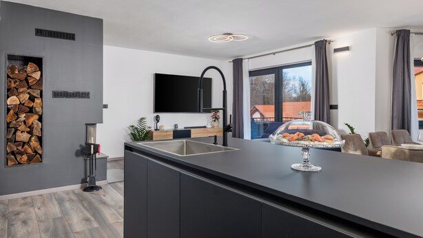 Une cuisine moderne dotée d’un îlot central, d’un four encastré et d’une grande fenêtre.