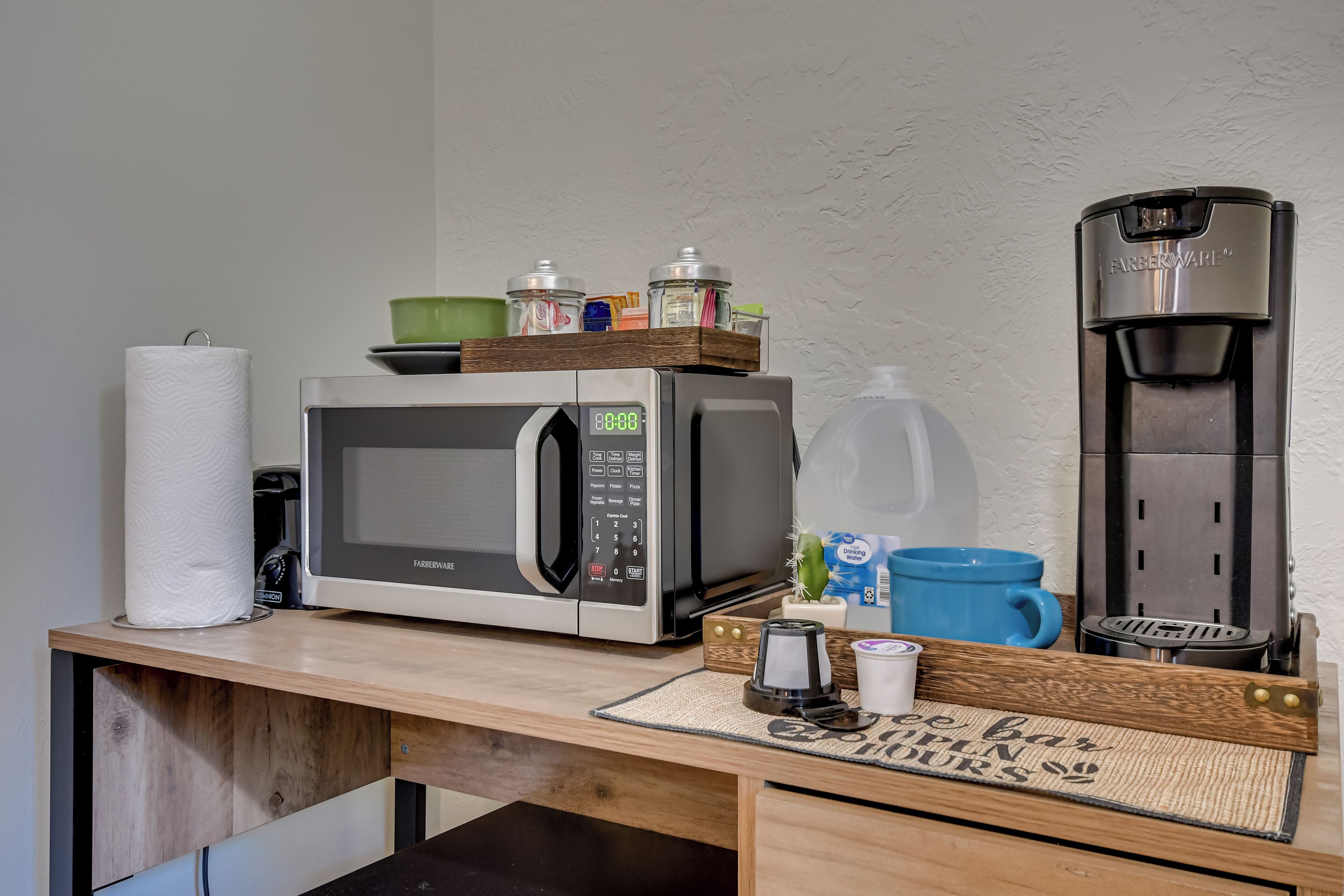 A kitchenette with a microwave, coffee maker, and various kitchen items on the counter.