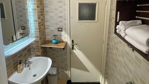 Une salle de bain avec un lavabo, un miroir, une porte et un porte-serviettes.