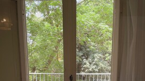 Une pièce avec un plancher en bois, une porte blanche donnant sur un balcon et une rambarde blanche.