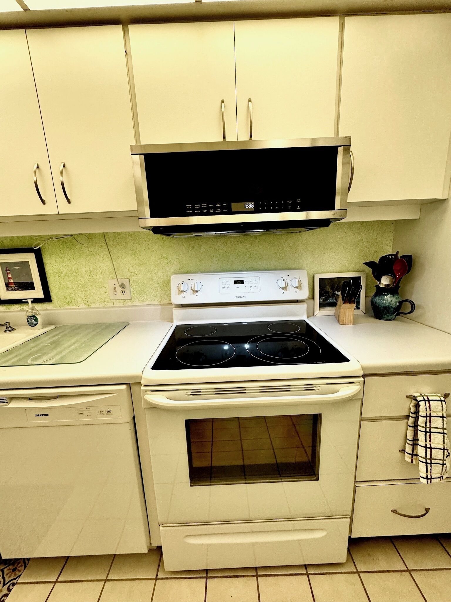 A kitchen with a stove, oven, and microwave. There are cabinets above the stove and a countertop with a sink.