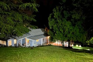 A house with a porch, a lawn, and trees surrounding it.