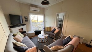 Una sala de estar con sofá, sillones, una mesa de centro y televisor.