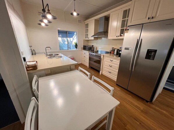 A modern kitchen with a central island, stainless steel appliances, white cabinetry, and pendant lighting.