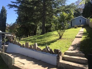 A residential property with a well-maintained lawn, a stone retaining wall, and a wooden fence.