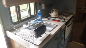 A compact kitchen with a gas stove, a sink, and a window. - Cozy RV, cheap with priceless features. (Hector)