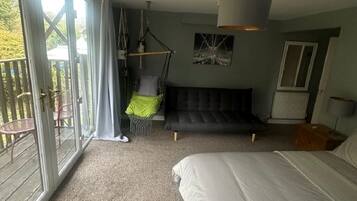 A bedroom with a large bed, a hanging chair, and a view of the outdoors through a sliding door.