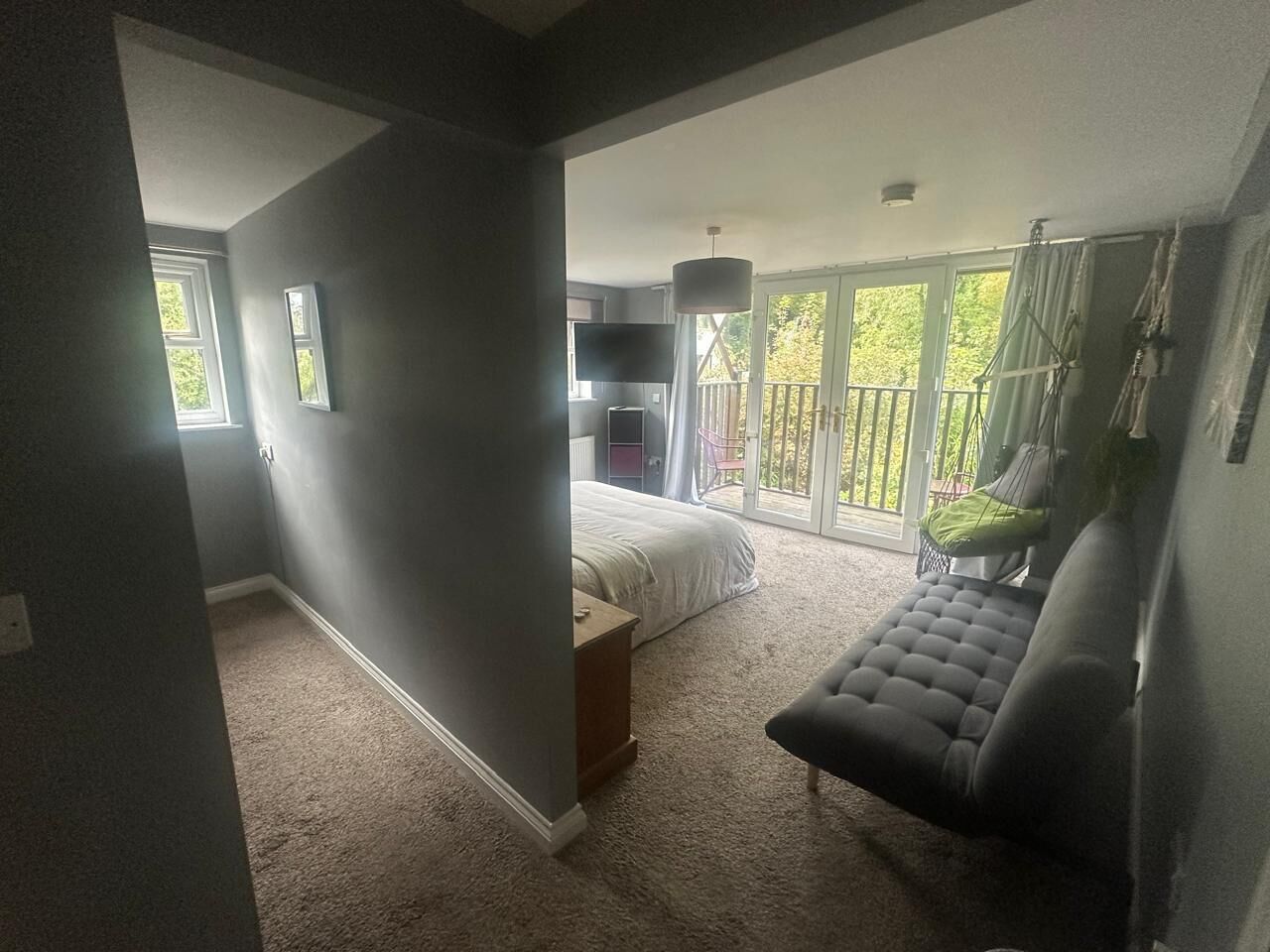Una habitación amplia con una cama grande, un sofá y un balcón con vistas a zonas verdes.