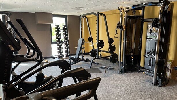 Et fitnesscenter med løbebånd, styrkemaskiner og vægte.