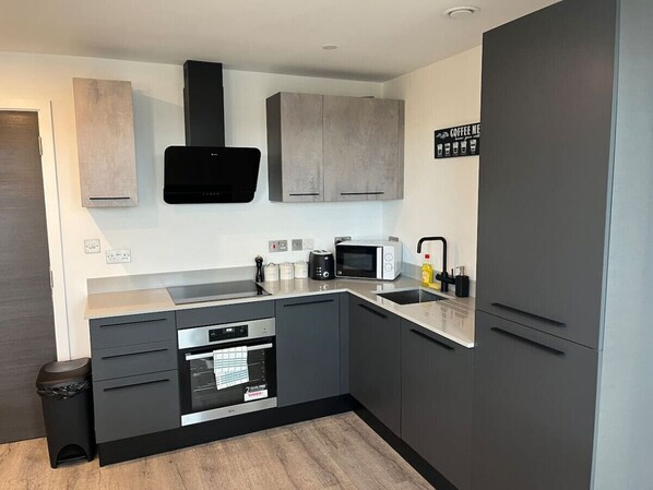 A modern kitchen with grey cabinets, a built-in oven, a microwave, and a coffee machine. - Superb citycentre new built flat and gym (York)