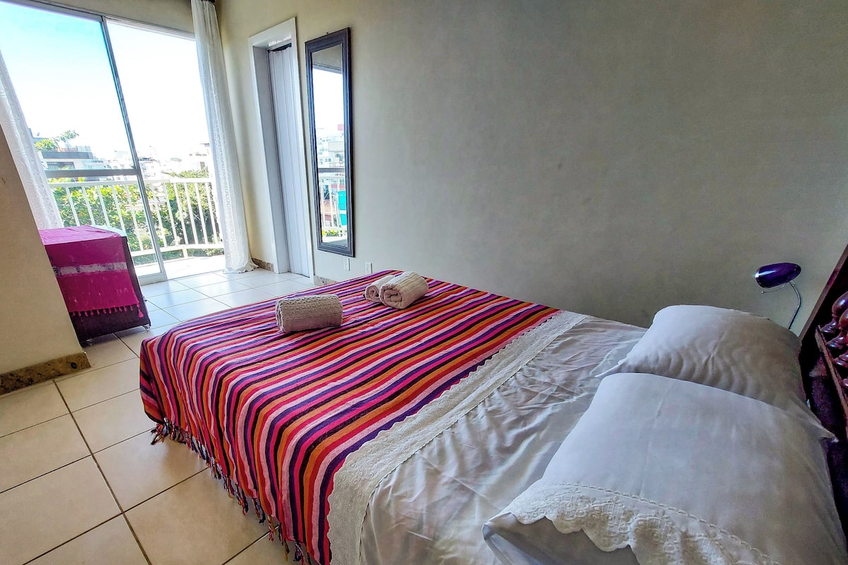 A hotel room with a bed, a window, and a balcony.