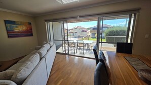 Ein Wohnzimmer mit einer Couch, einem Esstisch mit Stühlen und einer großen Schiebeglasdoor, die auf eine Terrasse im Freien führt.