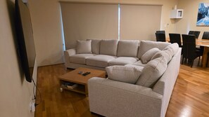 A living room with a sofa, a coffee table, and a dining area with chairs.