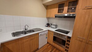 Eine kleine Küche mit Geschirrspüler, doppelter Spüle, Toaster und Backofen.