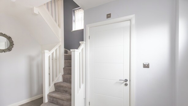 Un escalier menant à une porte, avec un interrupteur sur le mur à côté.