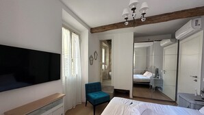 A bedroom with a bed, a TV mounted on the wall, a chair, and a mirror. - House in the shadow of the Colosseum (Roma)