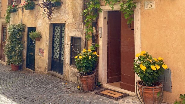 A historic building with multiple windows, some with shutters, and a door marked with the number 13. - House in the shadow of the Colosseum (Roma)