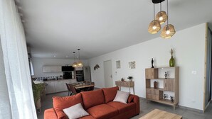 A modern living room with a sectional sofa, a wooden coffee table, and a dining area with a kitchen in the background. - le Cocon Vézerontin (Vézeronce-Curtin)