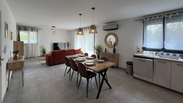 A modern kitchen with a dining area, featuring a wooden table, chairs, and pendant lights. - le Cocon Vézerontin (Vézeronce-Curtin)