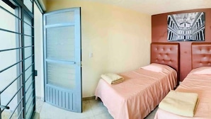 A room with two beds, a large window with a metal grid, and a wall-mounted artwork. - Casa San Rafael Guadalajara CENTRICO (Guadalajara)