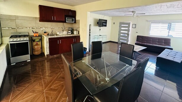 A modern kitchen with a gas stove, microwave, and a dining area with a glass table and chairs. - Casa San Rafael Guadalajara CENTRICO (Guadalajara)