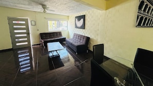 A spacious living room with a dark tiled floor, a ceiling fan, a sofa, a coffee table, and a TV. - Casa San Rafael Guadalajara CENTRICO (Guadalajara)