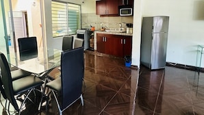 A spacious kitchen with dark wood flooring, a dining area with a glass table and chairs, and a refrigerator. - Casa San Rafael Guadalajara CENTRICO (Guadalajara)