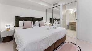 A modern bedroom with a large bed, bedside tables, a mirror, and a walk-in closet. - 1BR Apartment on North Terrace (Adelaide)