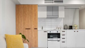 A modern kitchen with white cabinets, a wooden door, and a built-in oven. - 1BR Apartment on North Terrace (Adelaide)