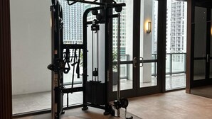 A gym with exercise equipment, large windows, and a view of tall buildings. - Sleek Urban Living Stylish 1BR in Brickell (Miami)