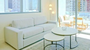 A modern living room with a white sofa, two round tables, and a view of high-rise buildings through large windows. - Sleek Urban Living Stylish 1BR in Brickell (Miami)