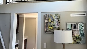 A multi-level home interior with a wooden ceiling, a staircase, a dining area, and a living room with a lamp and artwork. - Riverfront Tiny Home - Amazing Views (Strawberry Plains)