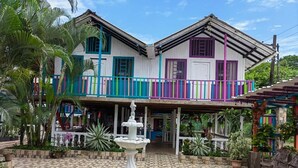 A two-story building with a balcony, a fountain, and a tiled patio area.