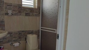 A bathroom with a toilet, a sink, and a toilet paper holder.