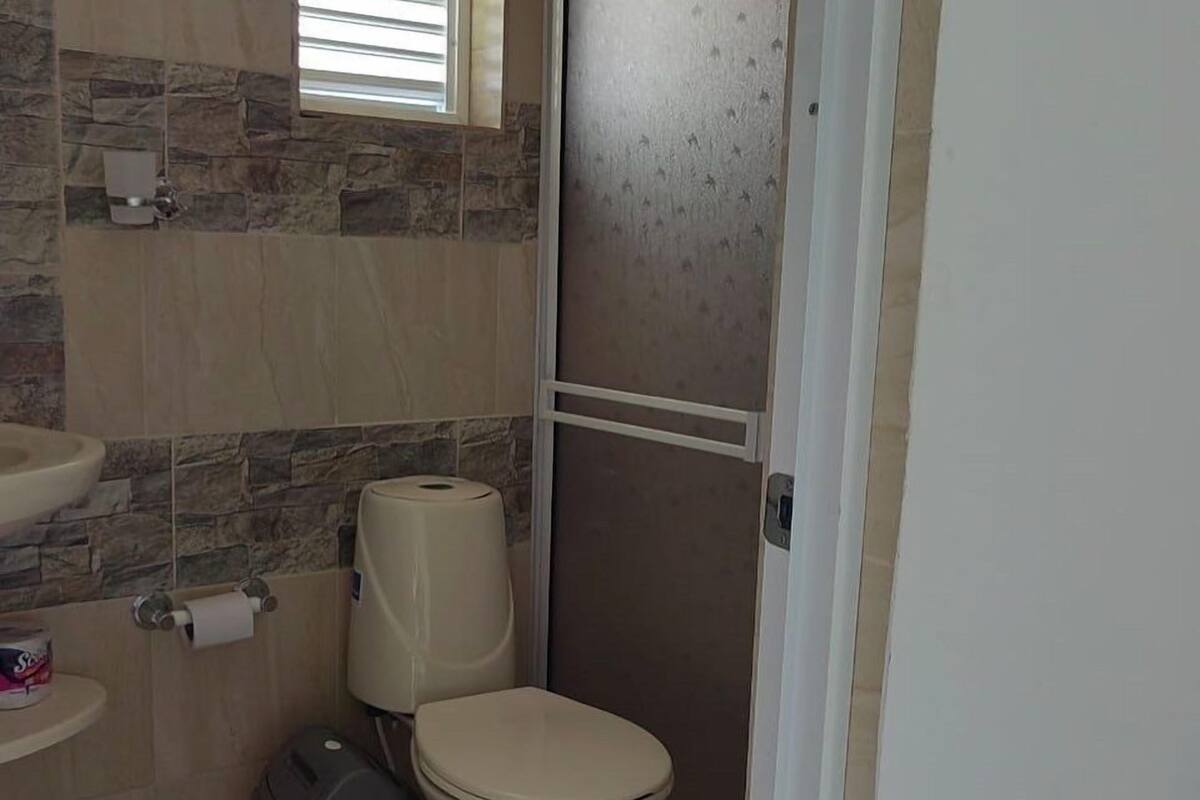 Un baño con inodoro, lavamanos y soporte para papel higiénico.