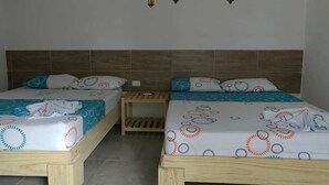 Two wooden beds with patterned bedding, a small wooden nightstand, and a wall with hanging lanterns.