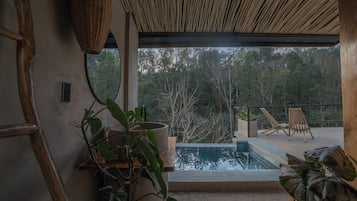 Ein modernes Interieur mit einem großen Fenster, das einen Pool und üppiges Grün zeigt.