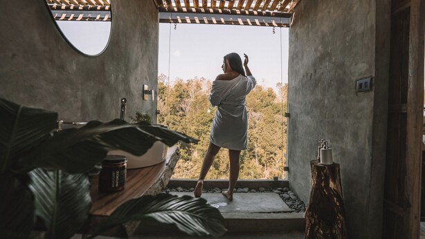 A person in a robe standing at a doorway with a view of trees. - Kafen Hotel  (Juayua)