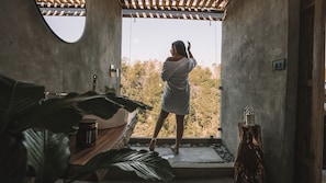 A person in a robe standing at a doorway with a view of trees. - Kafen Hotel  (Juayua)